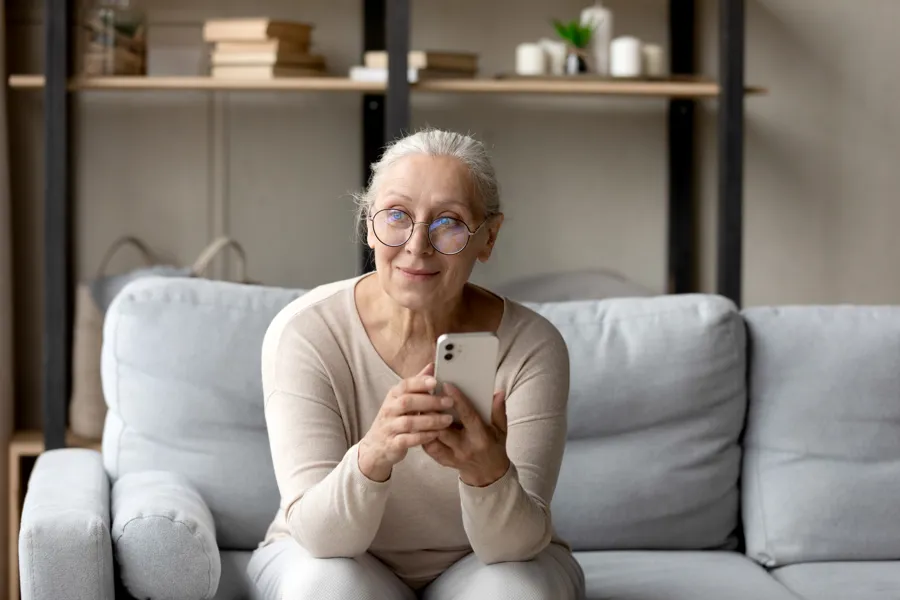 En person som sitter i en sofa og holder en telefon