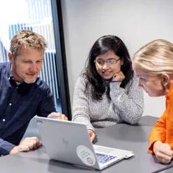 En gruppe mennesker som ser på en bærbar datamaskin