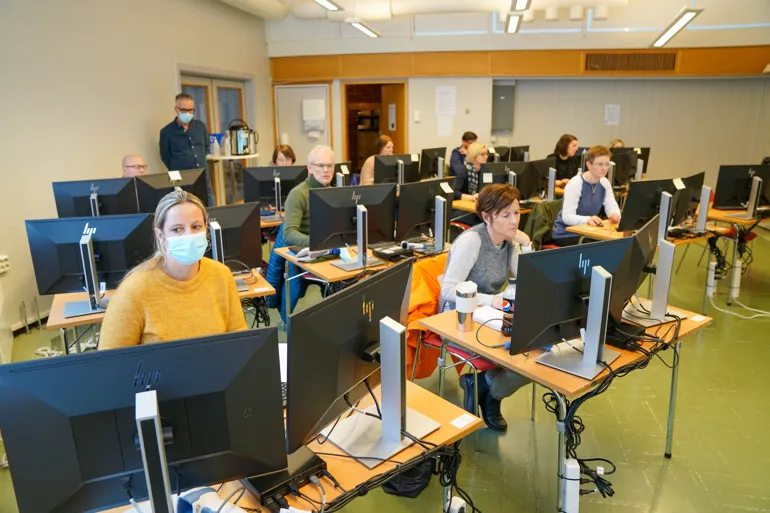 En gruppe mennesker som sitter ved datamaskiner