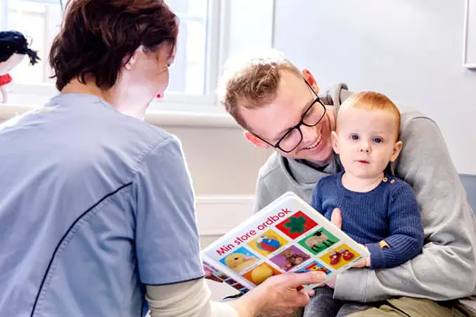 A man and woman reading a book to a baby