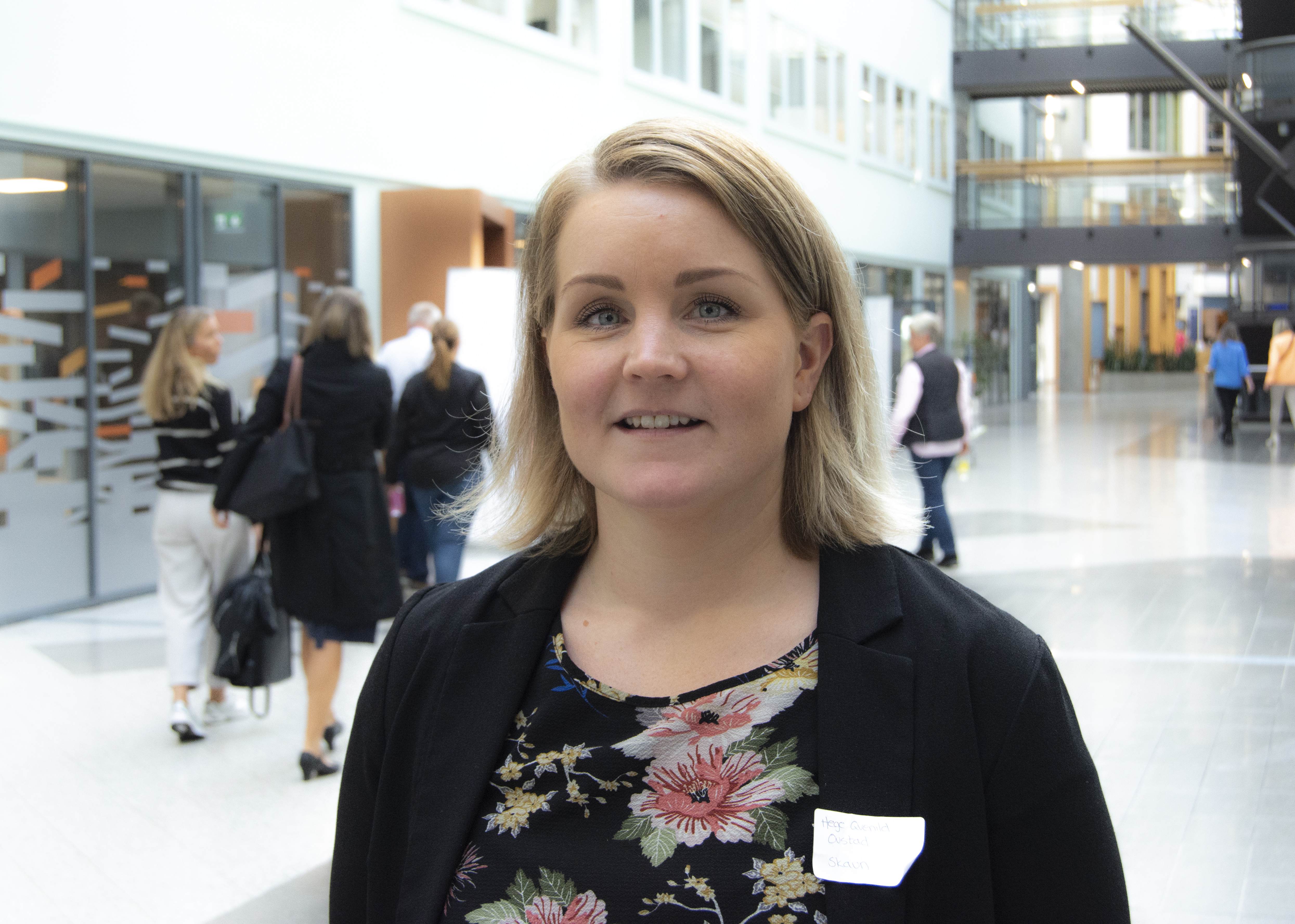 Kvinne i halvpositur står i stor korridor
