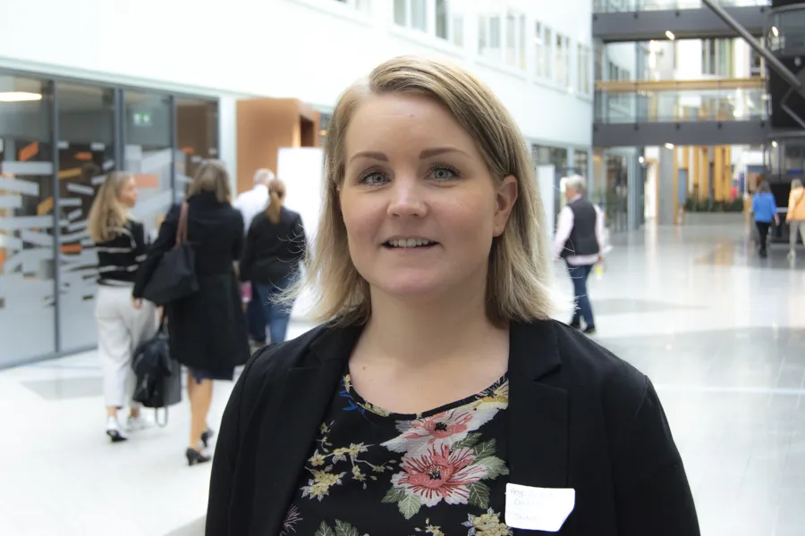 Kvinne i halvpositur står i stor korridor