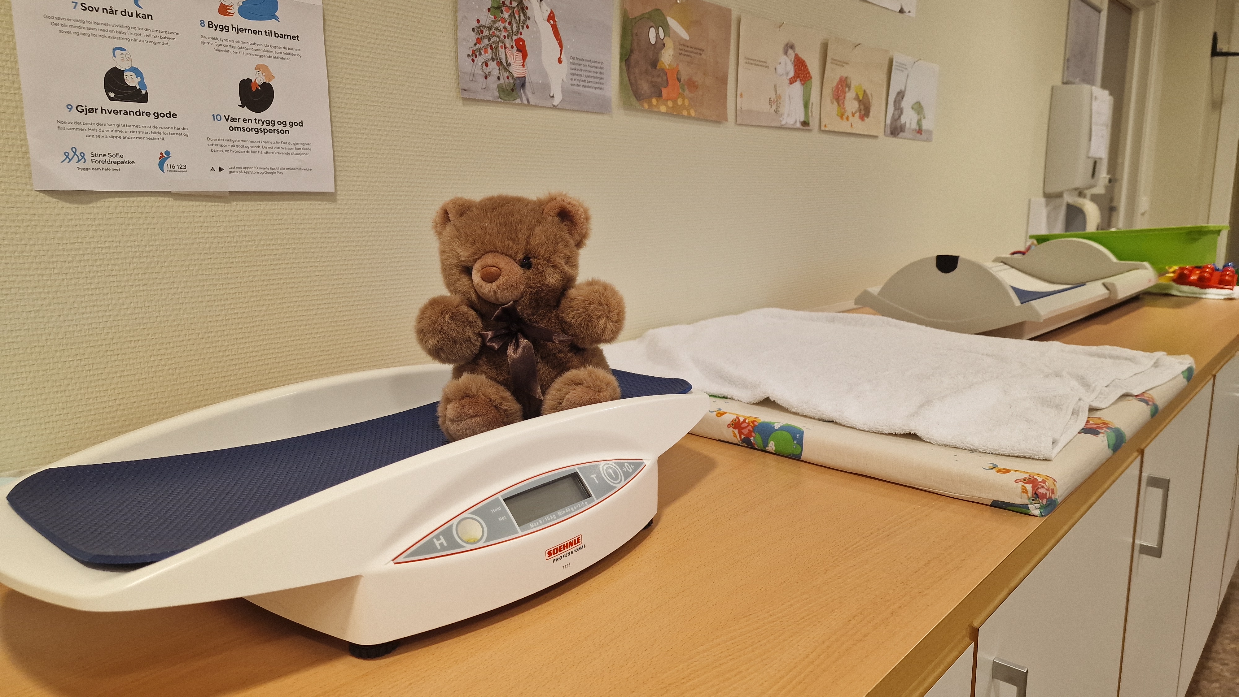 En teddybjørn som sitter på en babyvekt på en helsestasjon