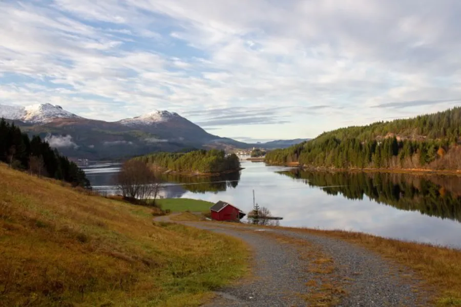 Motiv fra Heim kommune. Et lite rødt hus ved en innsjø