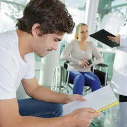 Ung mann leser i papirer på et sykehus