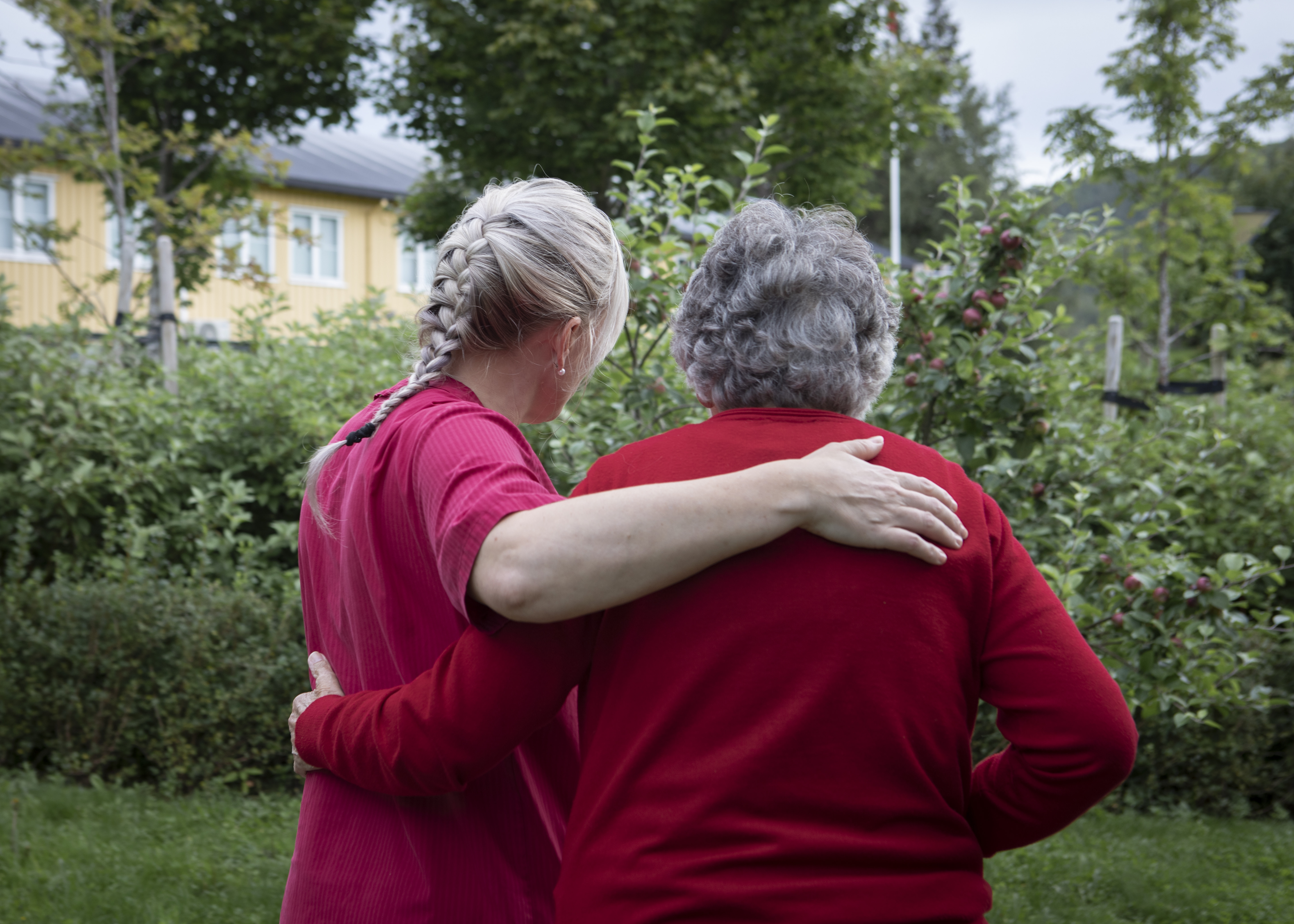 To kvinner avbildes bakfra som omfavner hverandre. Bildet gir en empatisk stemning.