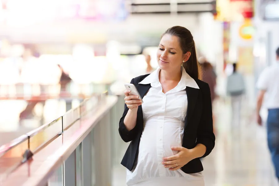 Gravid kvinne holder en smart-telefon.