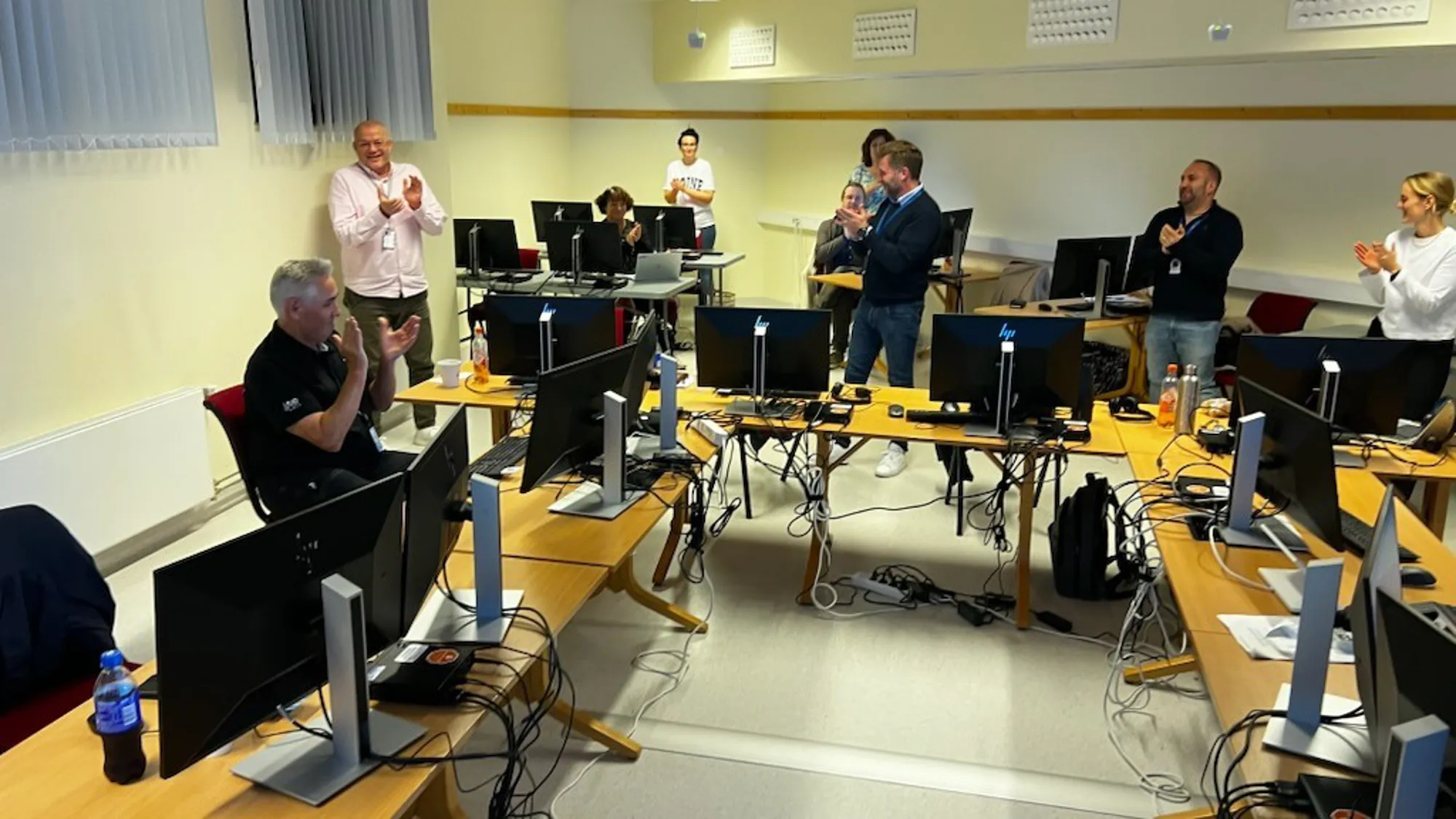En gruppe mennesker i et rom med datamaskiner