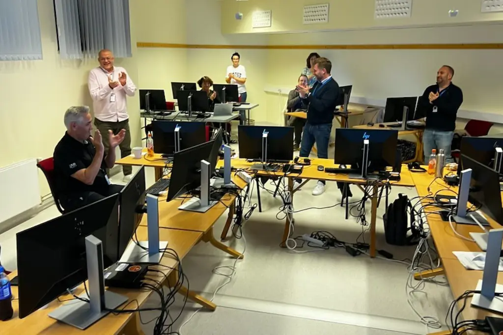En gruppe mennesker i et rom med datamaskiner