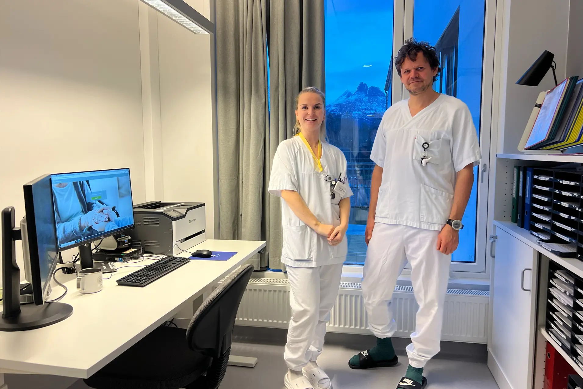 Et par menn i hvite labfrakker står foran en datamaskin