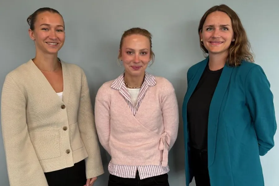 Tre møtedeltakere står foran en vegg, to av kvinnen er deltakere fra analysebyrået og i midten står ungdomsrepresentant for brukerutvalget i Helseplattformen