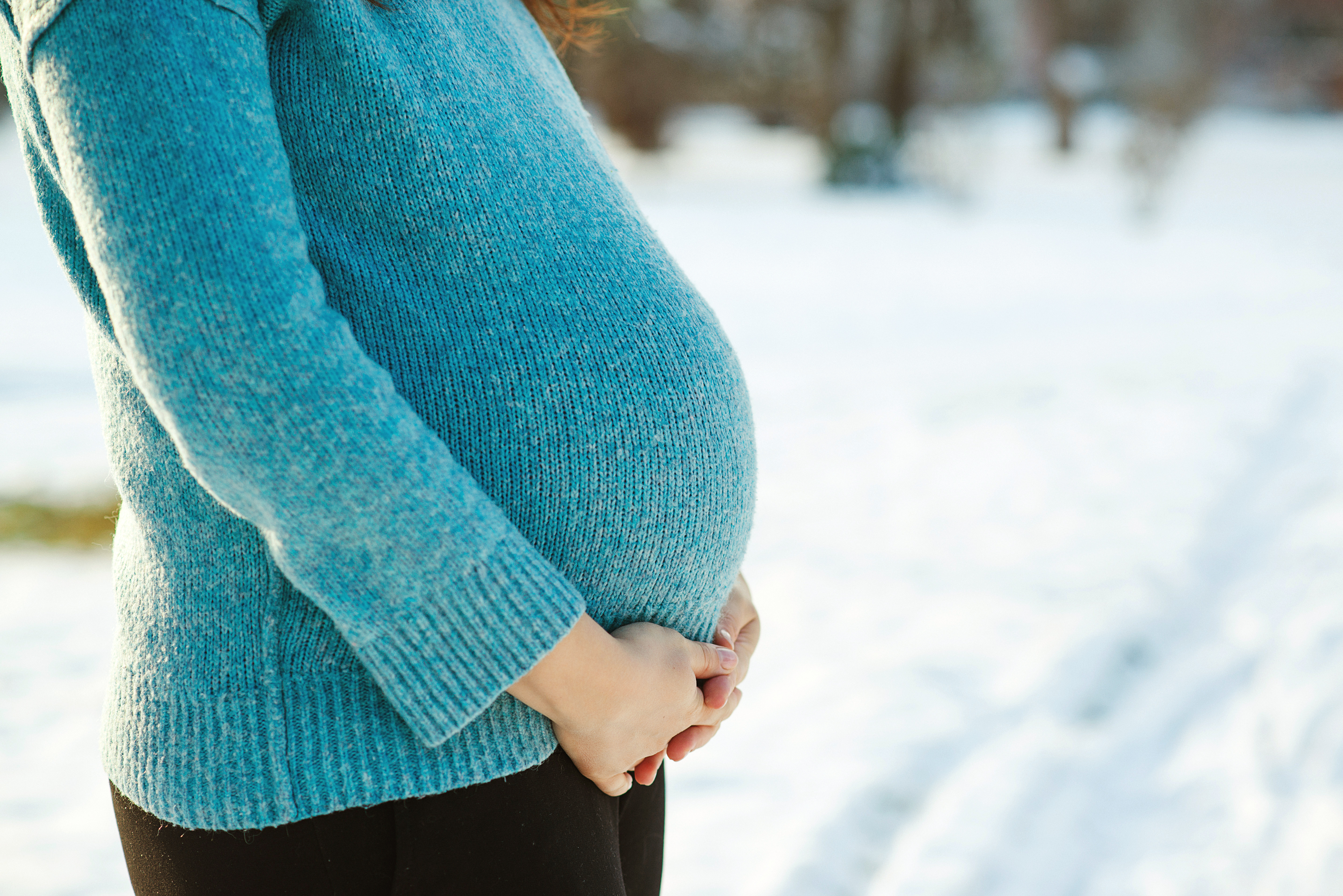 Kvinne sett fra siden med stor, gravid mage