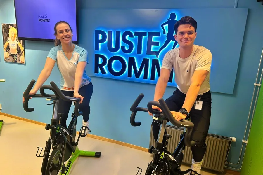 Fysioterapeut Sofie Hammernes Strømme og NTNU-student Joachim Sandor Knudsen sitter på spinningsykler på Pusterommet i Ålesund.