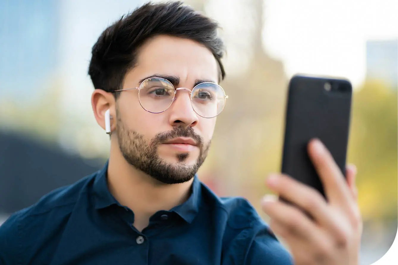 En mann i 20-årene holder en mobiltelefon