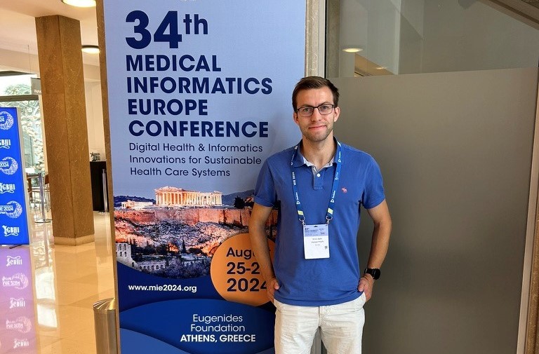 Emil Hægermark har skrevet masteroppgave og smiler foran et skilt