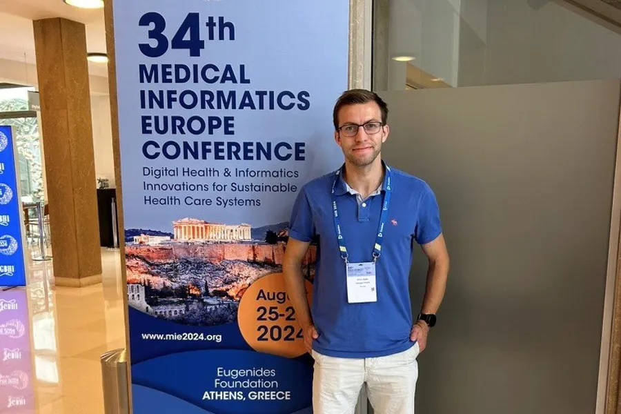 Emil Hægermark har skrevet masteroppgave og smiler foran et skilt