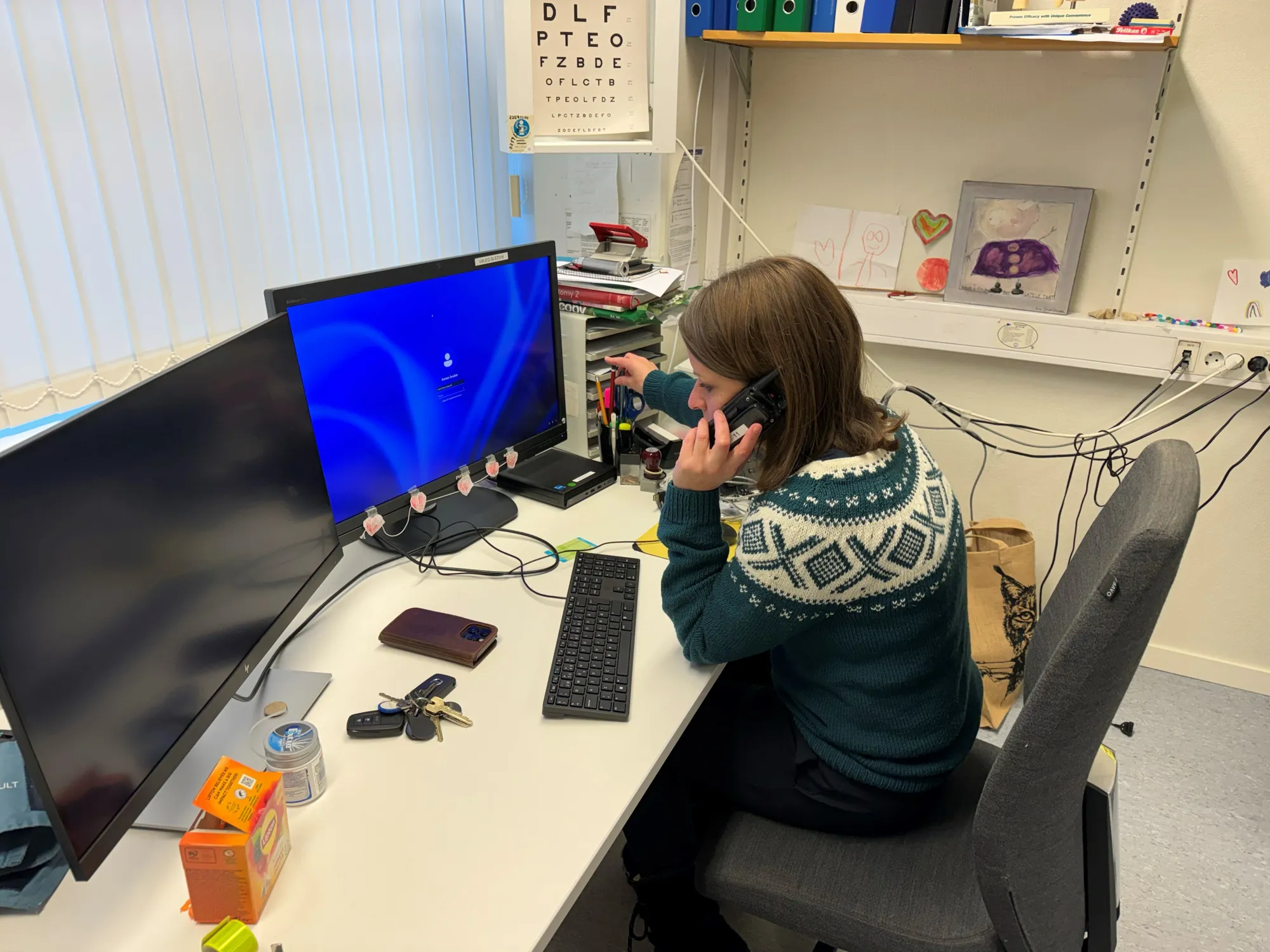 En mann som sitter ved et skrivebord med en datamaskin og en telefon